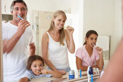 A family brushing their teeth together at the mirror